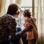 Grandmother and Granddaughter together looking out a window